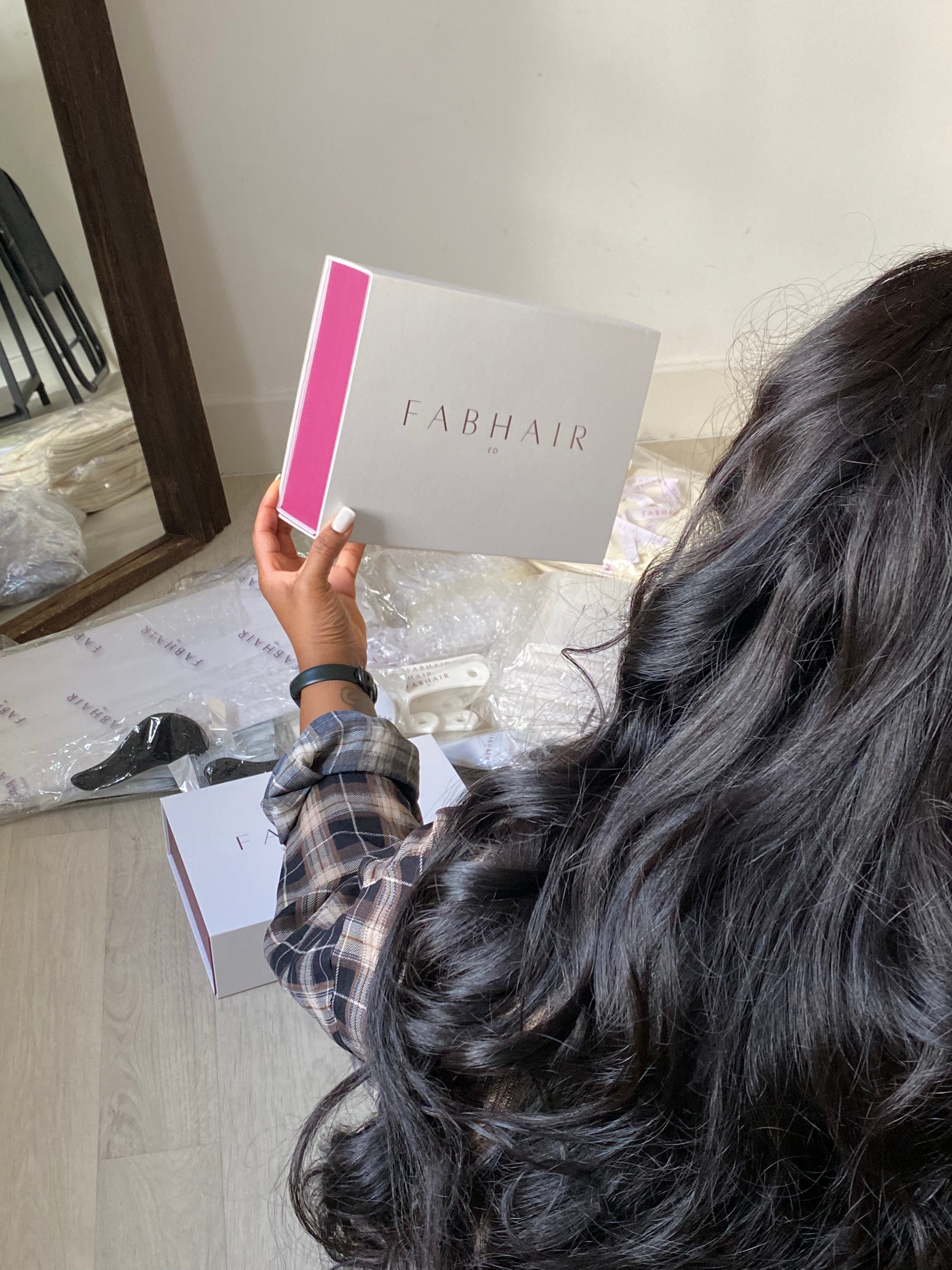 Person with long black hair holding a 'FABHAIRCO' product box.